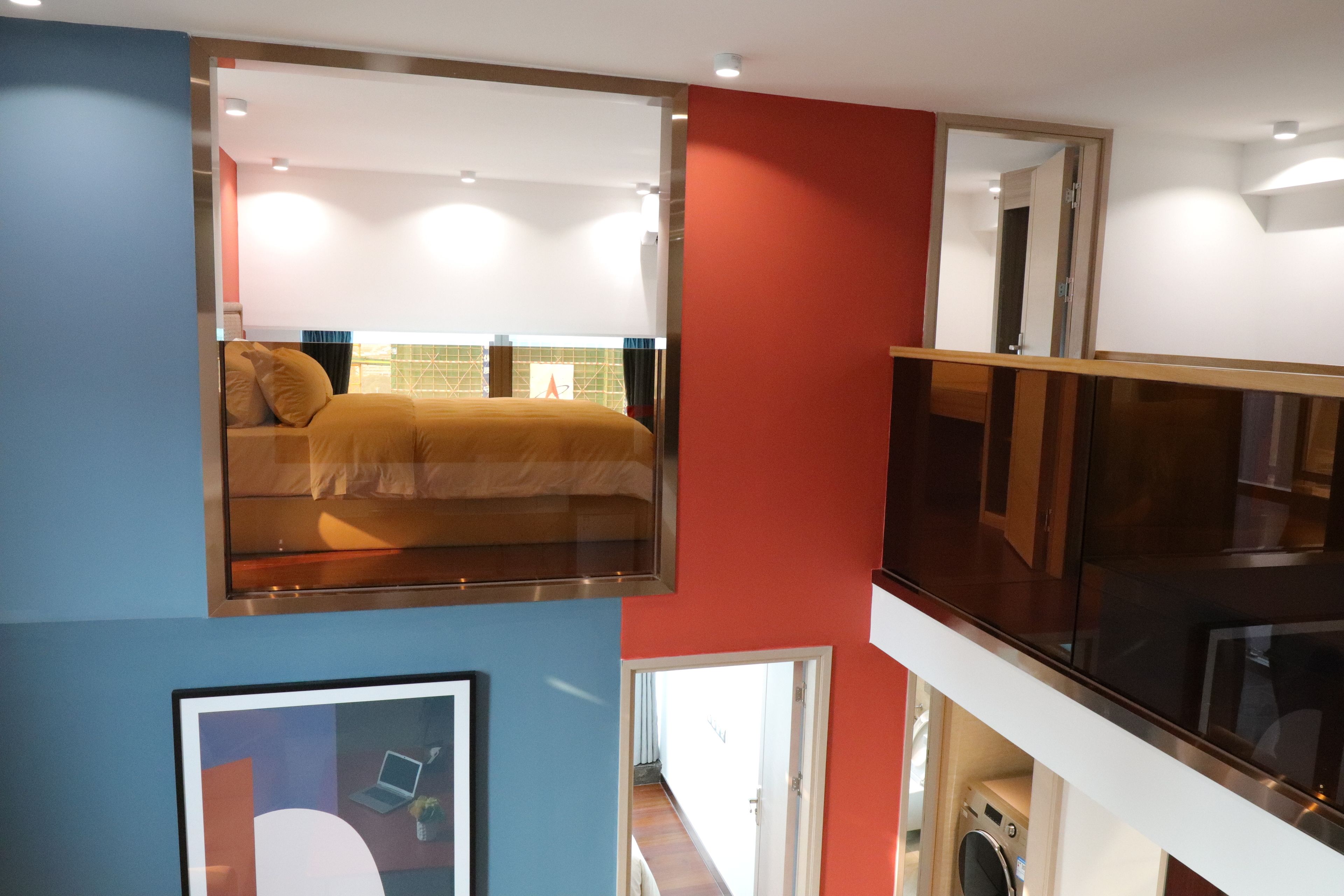 Une chambre d’hôtel à plusieurs niveaux, avec un lit à l’étage supérieur, une salle de bain avec douche et toilettes, et un balcon doté d’une rambarde en verre.