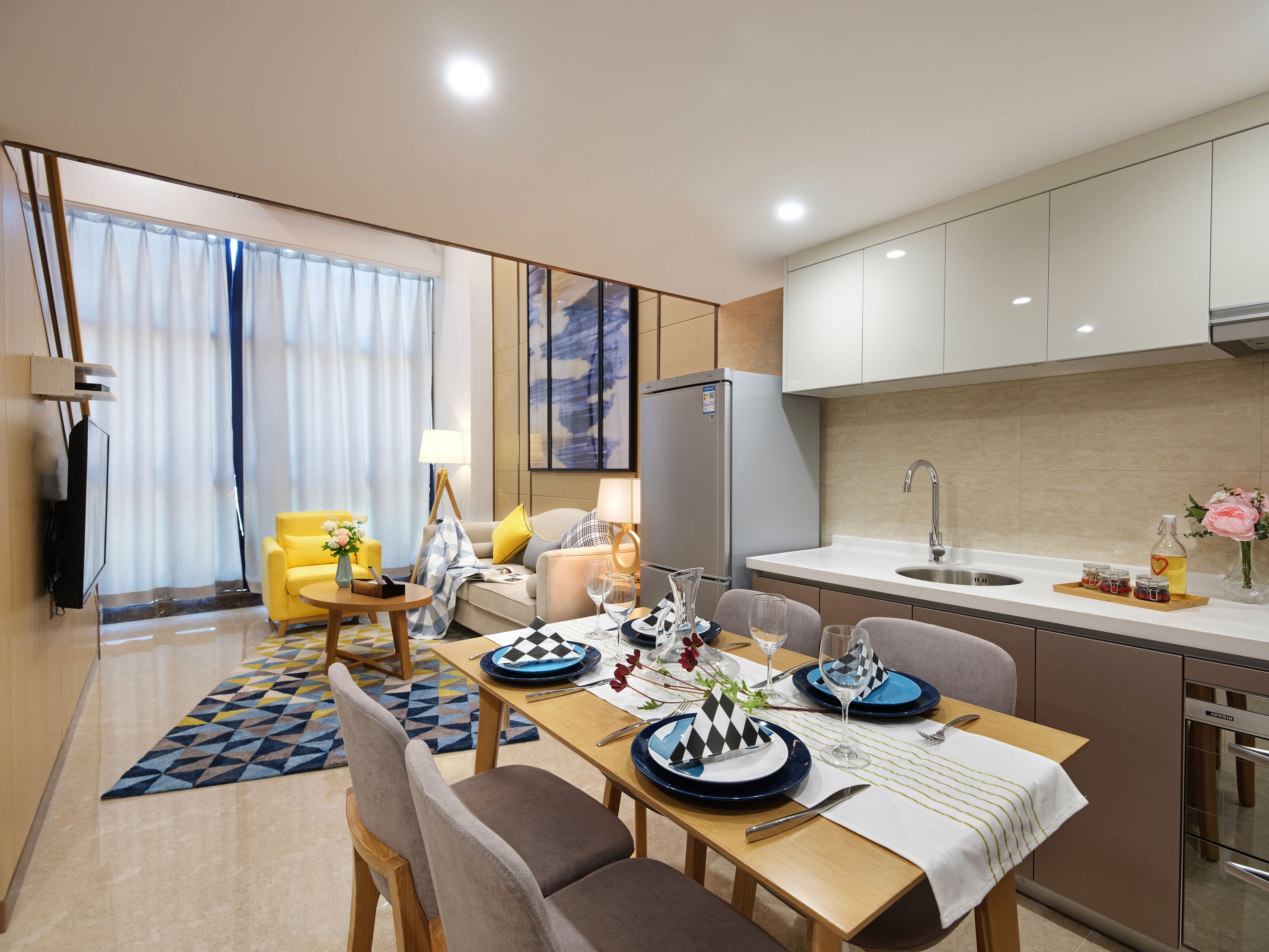 A modern hotel room with a dining area, a kitchen, and a living area.