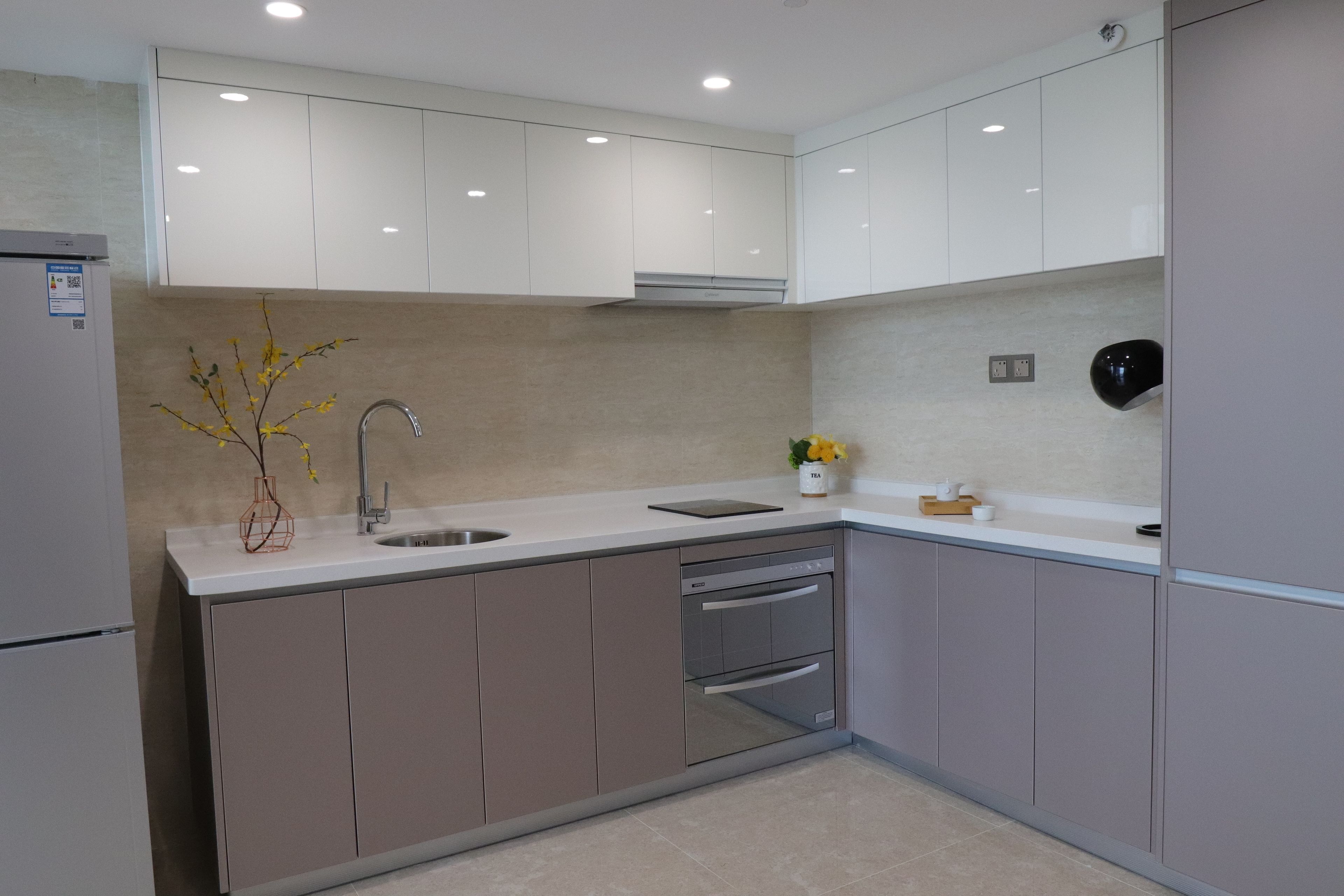 Una cocina moderna con armarios blancos, un lavamanos de acero inoxidable y un horno empotrado.