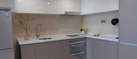 Una cocina moderna con armarios blancos, un lavamanos de acero inoxidable y un horno empotrado.