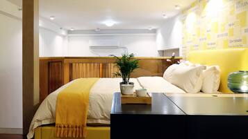 A hotel room with a bed, bedside table, and a wall with yellow posters.