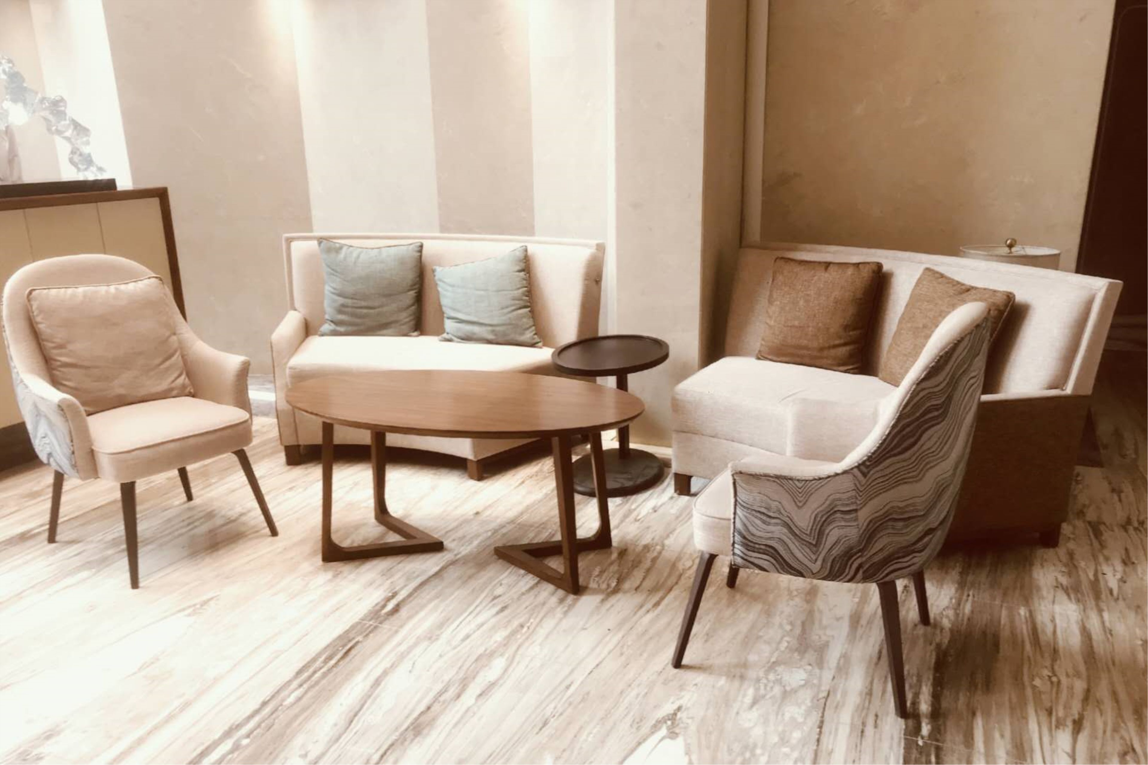 Una sala moderna con un sofá, dos sillones y una mesita redonda.