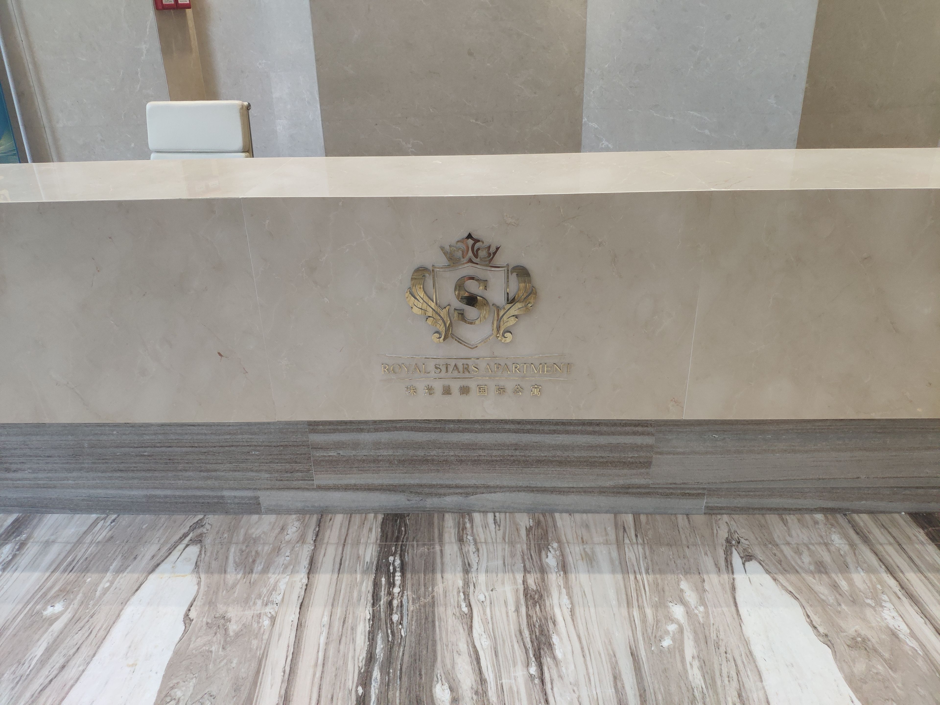 A reception desk with a marble top and a logo that reads "ROYAL STARS APARTMENT".