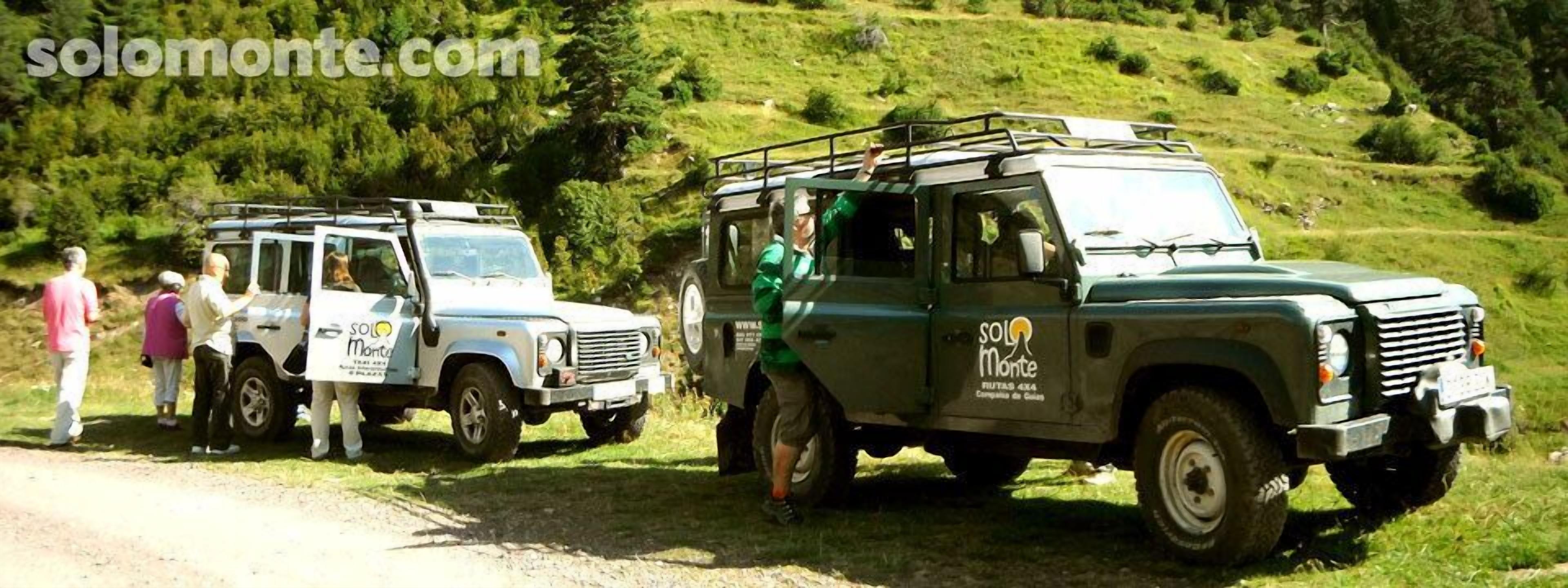 Un vehículo todoterreno blanco y uno verde estacionados en un camino de tierra, con gente cerca.