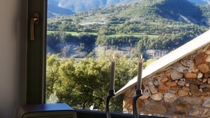 A window with a view of mountains, a stone wall, and a radio on the windowsill. - El Capricho de Nieves (Laspuna)