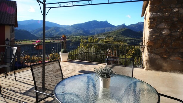 A balcony with a glass table and chairs, overlooking a mountainous landscape. - El Capricho de Nieves (Laspuna)