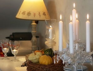 A table with a lamp, candles, a glass candle holder, and a basket of pumpkins. - El Capricho de Nieves (Laspuna)