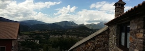 A stone building with a tiled roof, overlooking a valley with mountains in the background. - El Capricho de Nieves (Laspuna)
