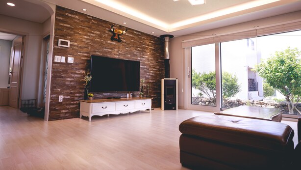 Un salon moderne doté d’un téléviseur à écran plat, d’un mur en bois et de grandes fenêtres.
