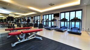 Une salle de sport équipée de tapis de course, de bancs et d'appareils d'exercice.