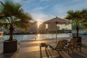 A rooftop pool area with lounge chairs, umbrellas, and palm trees. - Holiday Home Setapak Central Mall KL (Kuala Lumpur)