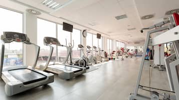 Un gimnasio con cintas de correr, bicicletas estáticas y máquinas de pesas.