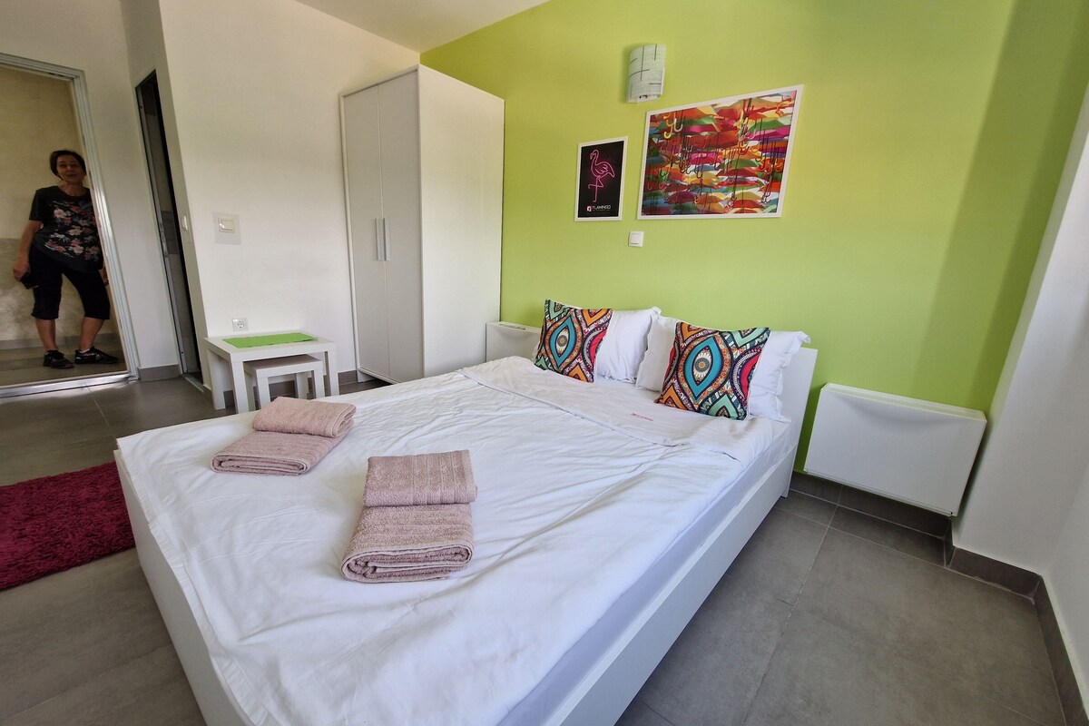 A hotel room with a bed, pillows, a desk, and a chair.