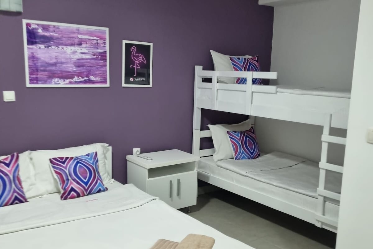 A bedroom with a bunk bed, a single bed, and a nightstand. There are two pillows on the single bed and two towels on the bed.