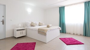 A modern bedroom with a bed, nightstand, and two rugs. - Flamingo resort (Belgrade)