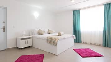 Un dormitorio moderno con cama, mesita de noche y dos alfombras.