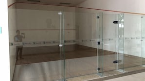 Ein Squashplatz mit Glaswänden und Holzboden.
