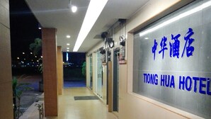 Un couloir menant à l’entrée d’un hôtel, avec une enseigne indiquant « TONG HUA HOTEL » en chinois et en anglais.