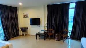 Une chambre d’hôtel avec un lit, un bureau et une chaise, une télévision et une vue sur l’extérieur.