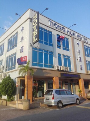 A hotel building with large windows and a sign that reads "Tiong Hua Hotel".