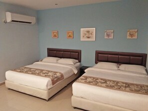 A hotel room with two beds, a wall-mounted air conditioner, and four framed pictures on the wall.