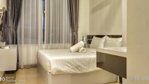 A hotel room with a bed, a bedside table, a lamp, and a window with curtains. - The Wave by ExcluSuites Malacca (Malacca City)