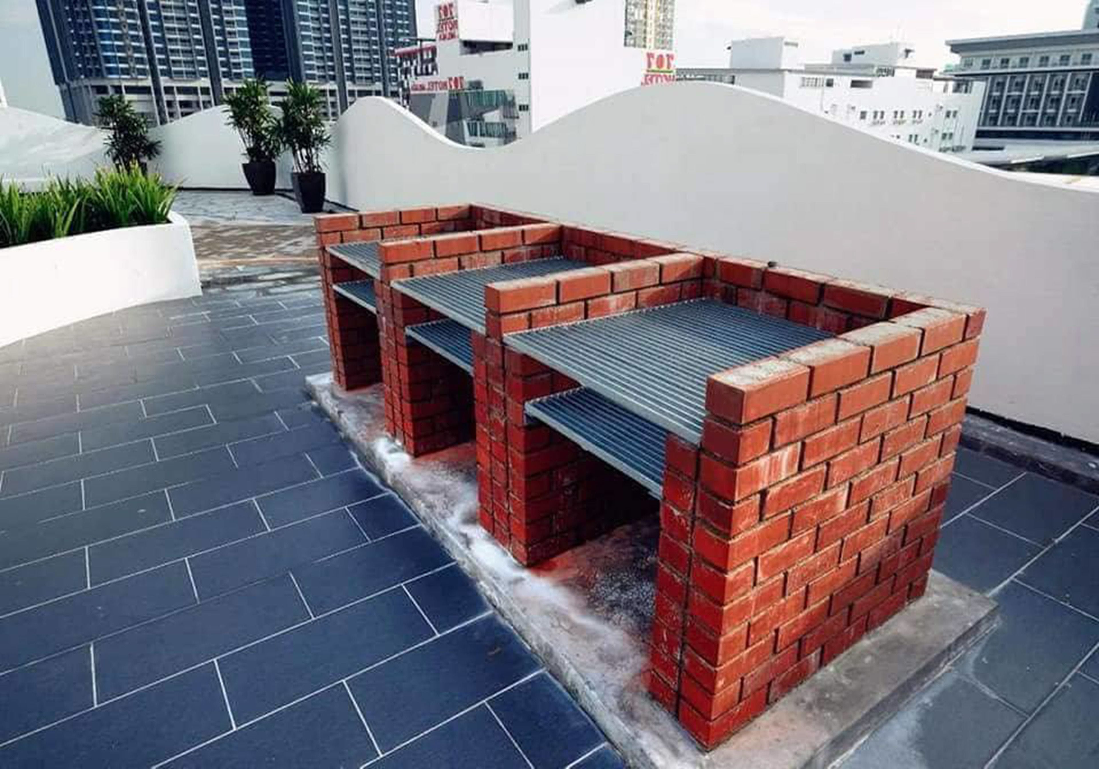 A rooftop patio with a brick barbecue area and potted plants.