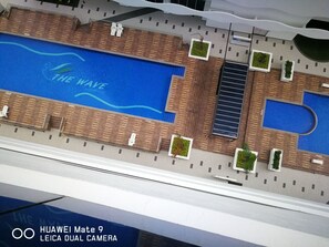 A model of a hotel with a swimming pool labeled "THE WAVE," outdoor seating, and a modern architectural design.