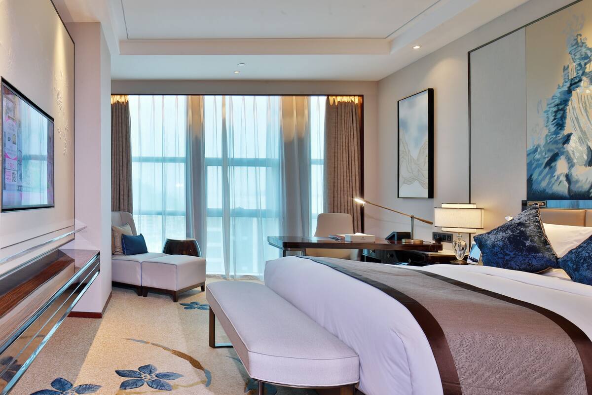 Una habitación de hotel con una cama grande, un sofá, un escritorio y un televisor.
