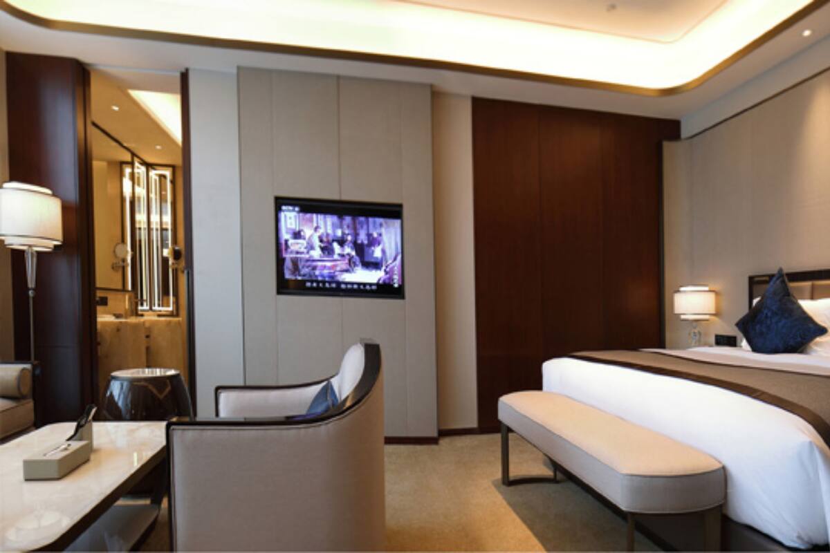 Una habitación de hotel con cama, escritorio, silla, televisión y mesita de noche.