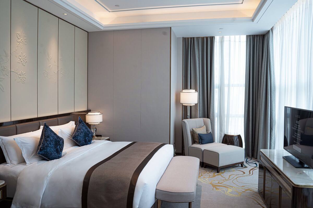 Una habitación de hotel con una cama grande, un escritorio, una silla y un televisor.