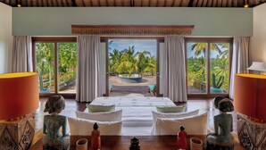 Un dormitorio con un ventanal grande, una cama y vistas a palmeras.