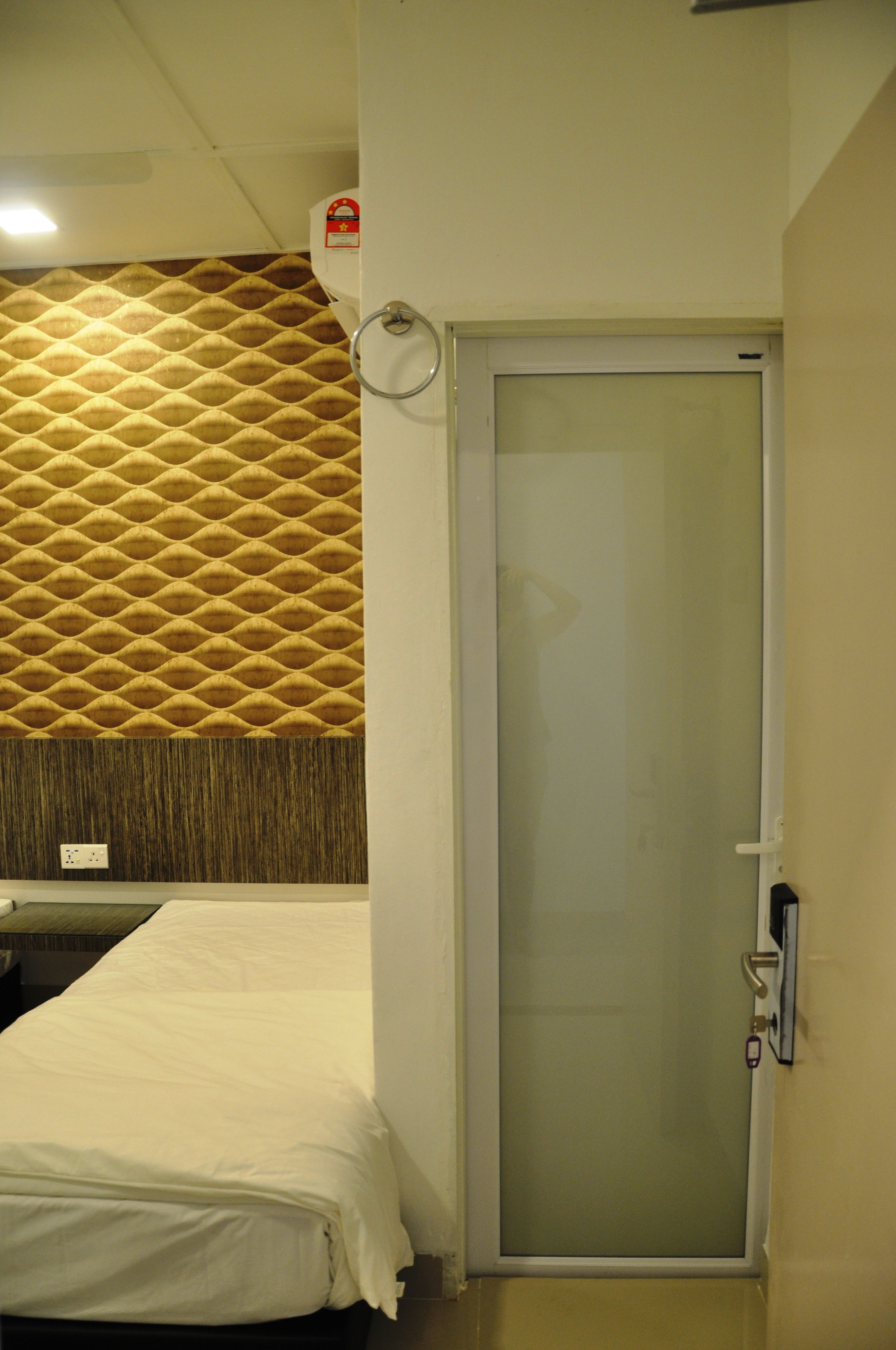A hotel room with a bed, a shower, and a textured wall.