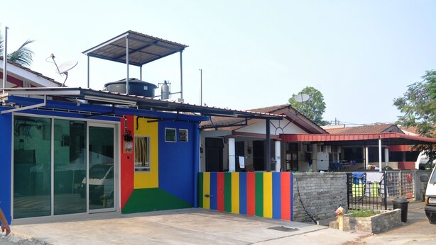 A colorful building with a glass door, a metal roof, and a concrete ground. - dr96inn (Kuantan)