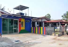 Un edificio colorido con puerta de vidrio, techo metálico y suelo de concreto.