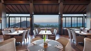 Un restaurant doté de nombreuses tables et chaises, avec de grandes fenêtres offrant une vue sur les montagnes.