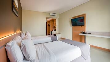 A hotel room with two beds, a TV mounted on the wall, a desk, and a shelf with a book.