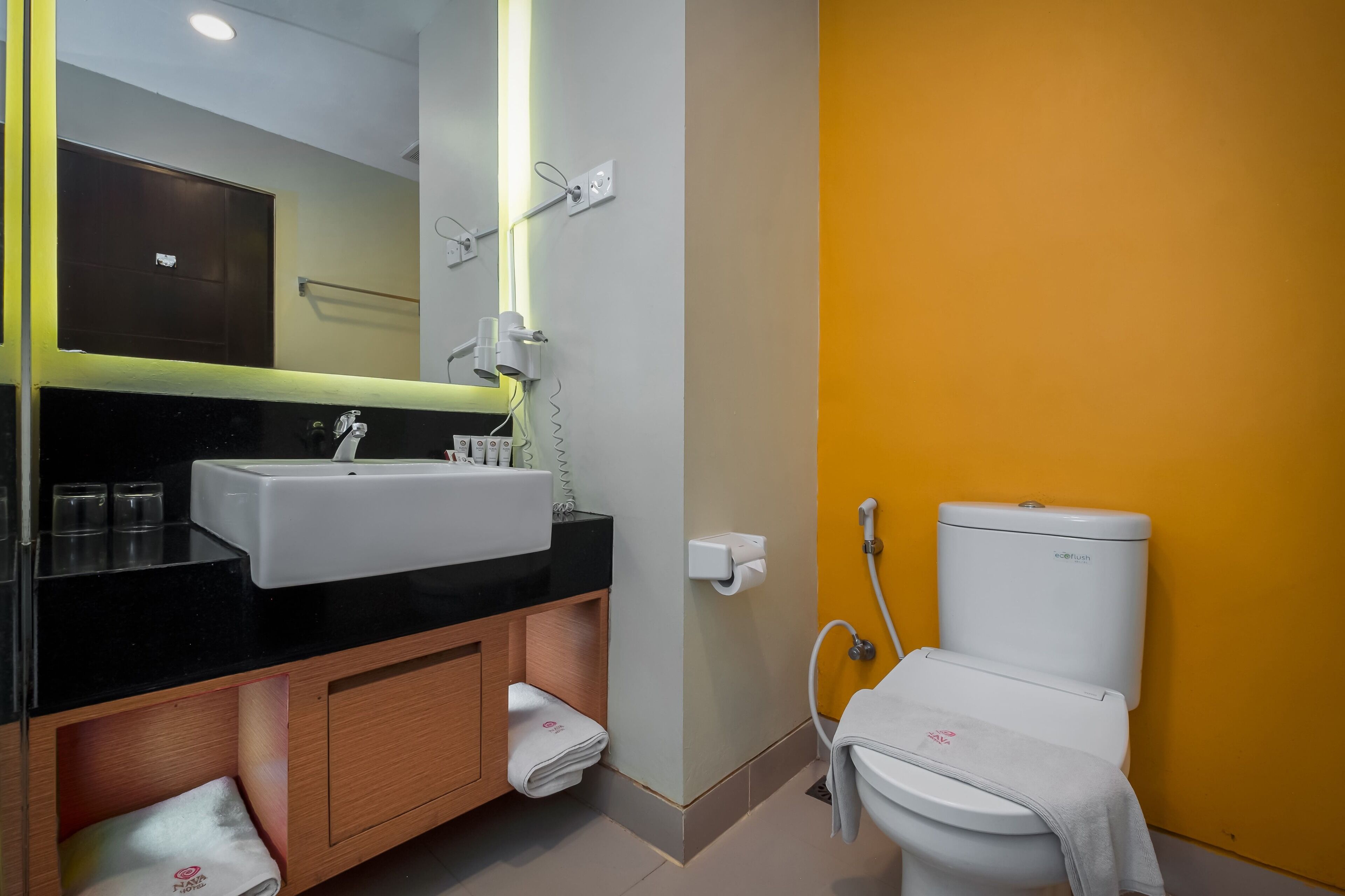 Un baño moderno con lavamanos de superficie negra, un espejo, un inodoro y un perchero para toallas.