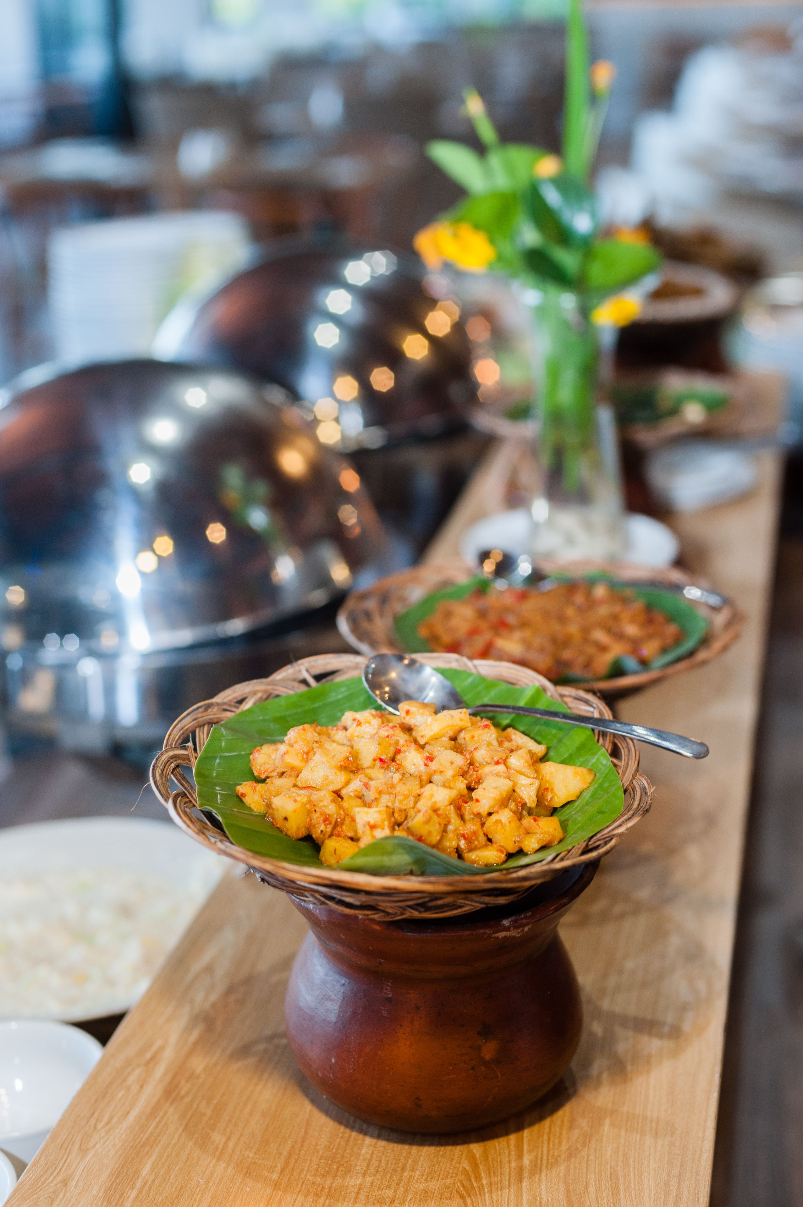 A table with various dishes served on banana leaves and traditional pottery.