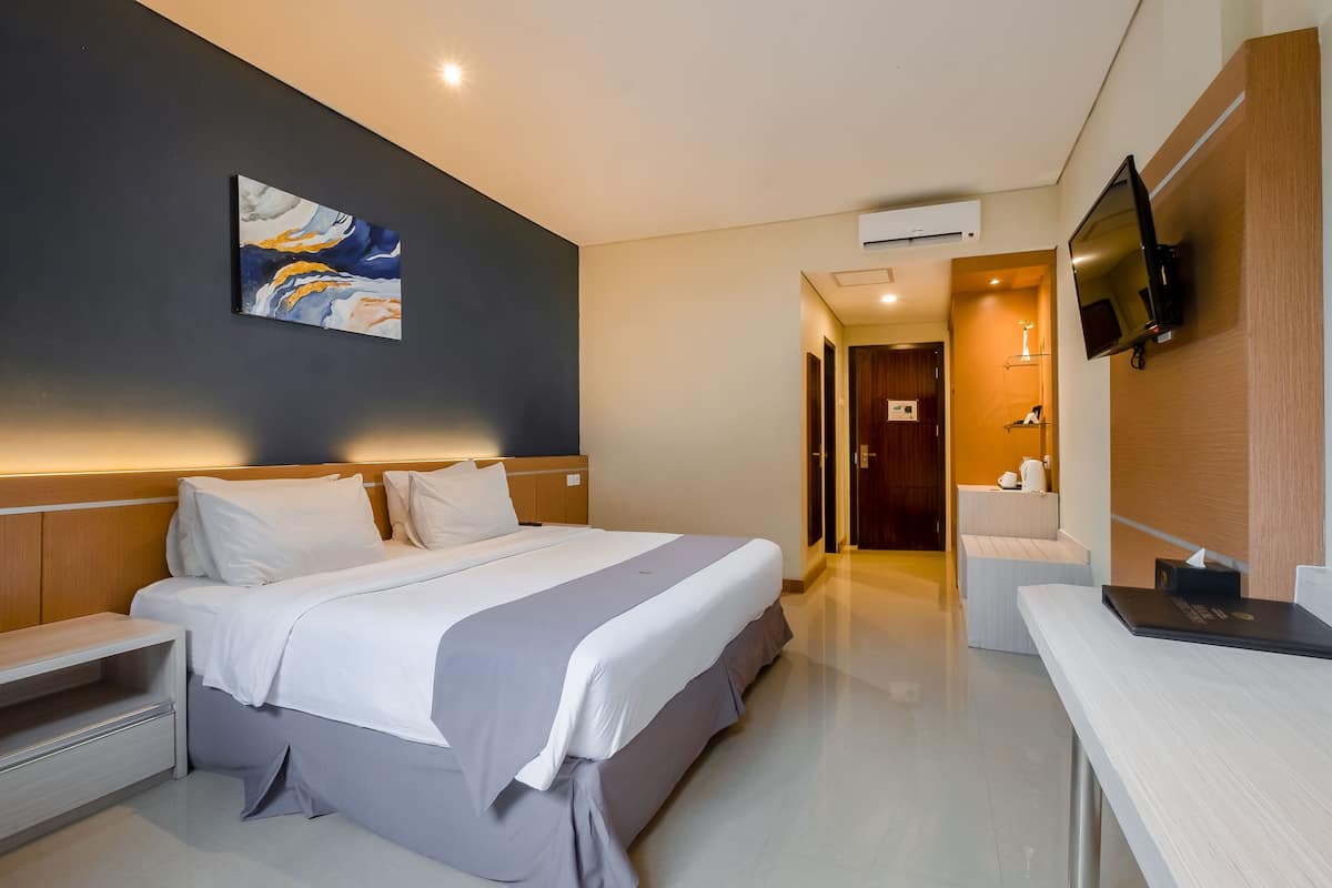 A modern hotel room with a large bed, bedside tables, a TV mounted on the wall, and a painting on the wall.