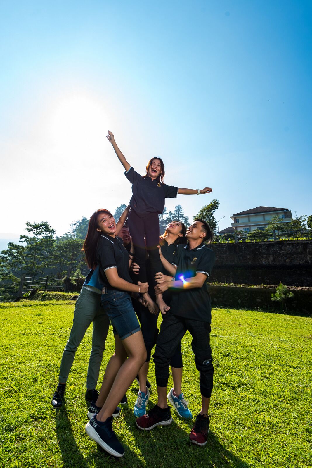 A group of people in a grassy outdoor area with a building in the background.