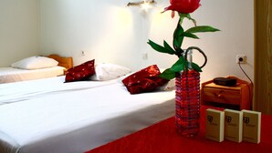 A hotel room with a bed, a red vase with a flower, and a small wooden nightstand with a lamp and a box. - Hotel Restaurant 'T Holt (Diepenheim)