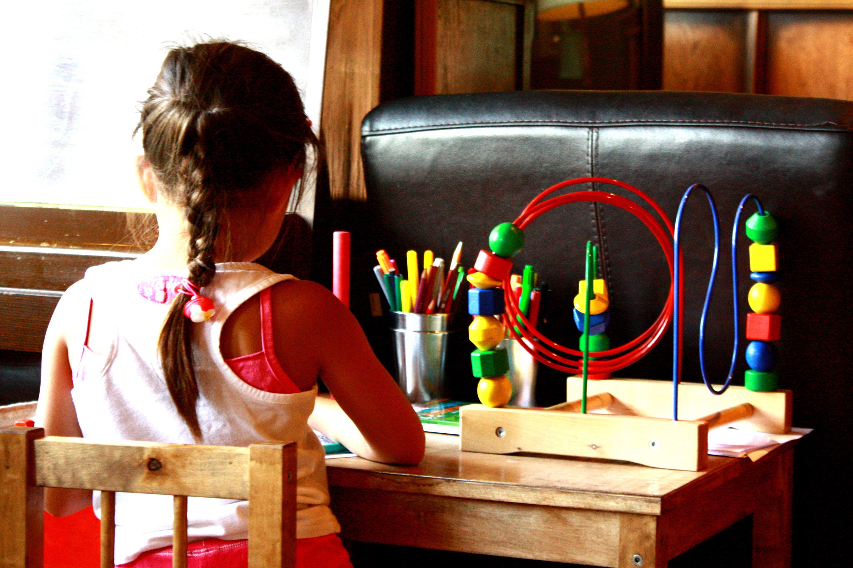 Un niño en una mesa de madera con un juguete.