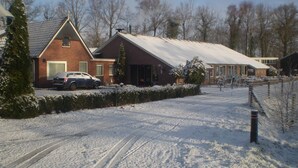 A residential area with a brick house, a car, and a snow-covered landscape. - Hotel Restaurant 'T Holt (Diepenheim)