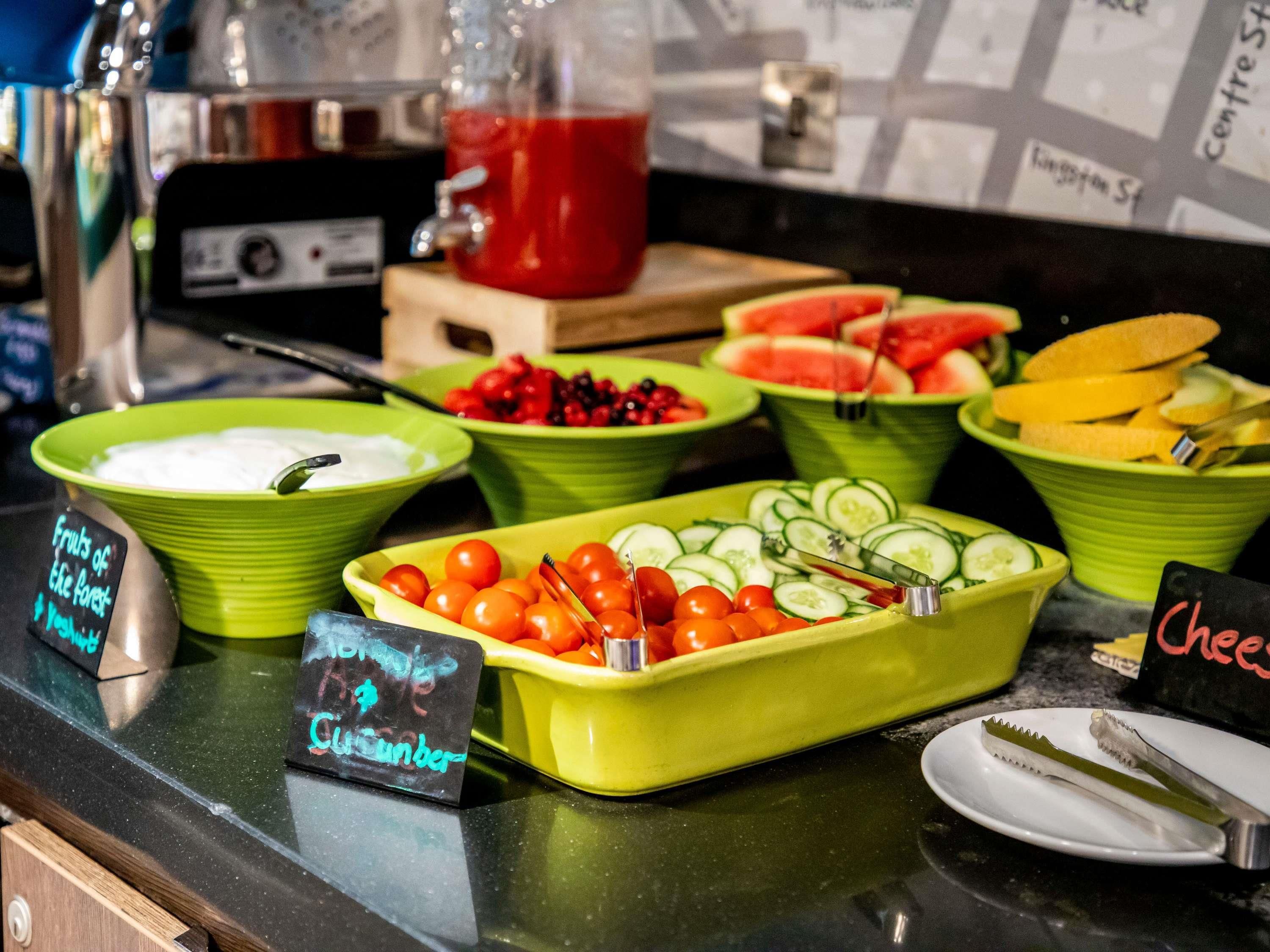 A buffet with various food items including fruits, vegetables, and a cheese dish.
