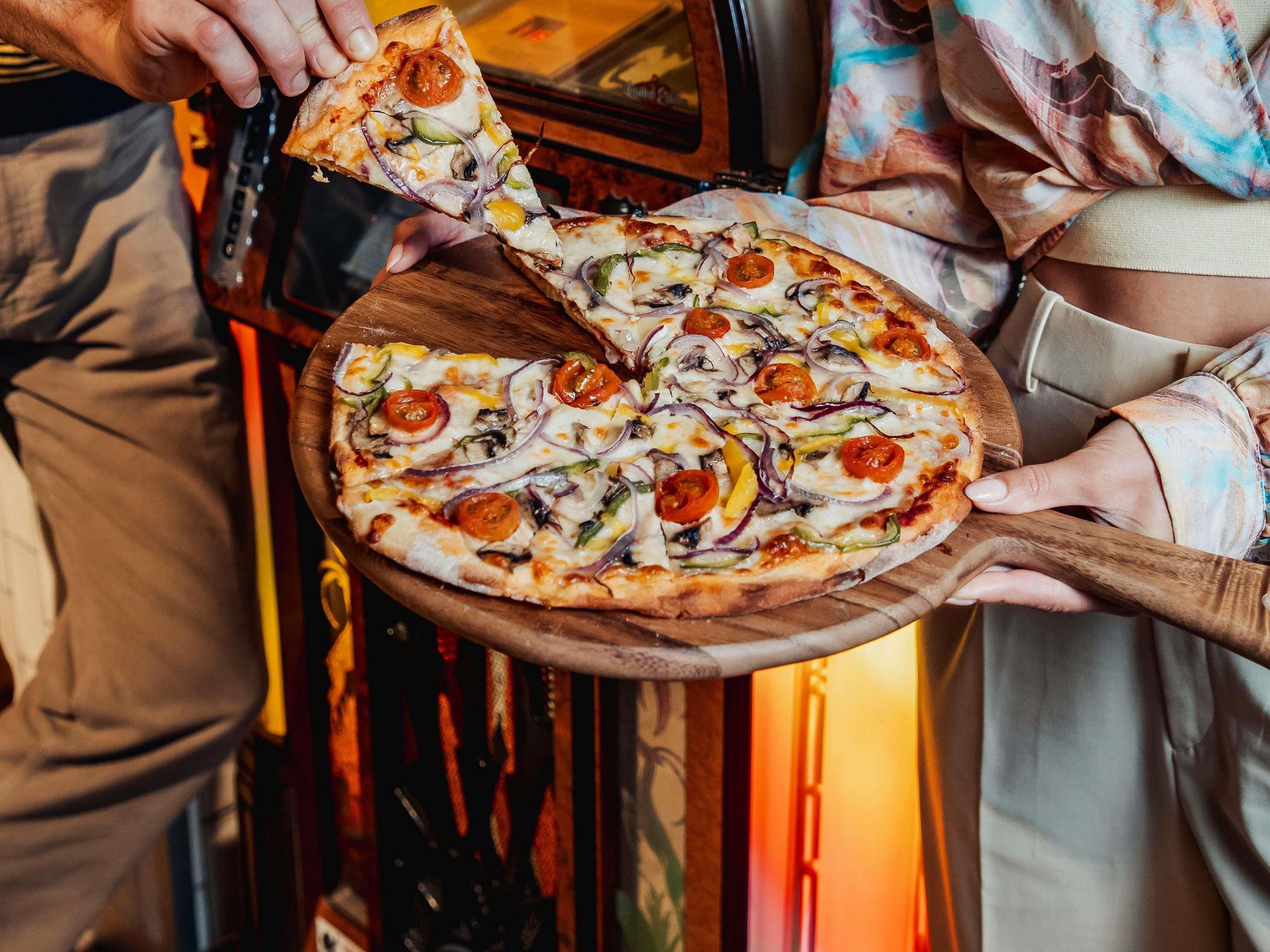 Eine Pizza mit verschiedenen Belägen auf einem Holzboden.