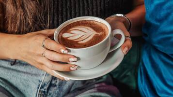 Une personne tenant une tasse de café ornée d’un motif en latte art.