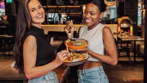 Two people holding a bowl of food at a pool table in a bar setting. - Ibis Styles Glasgow Central (Glasgow)