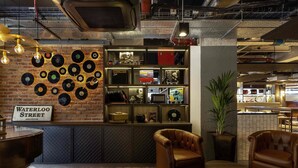 A cozy lounge area with a brick wall, vinyl records, and leather furniture.