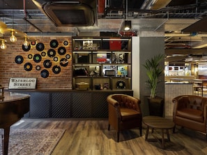 A cozy lounge area with a brick wall, vinyl records, and leather furniture. - Ibis Styles Glasgow Central (Glasgow)